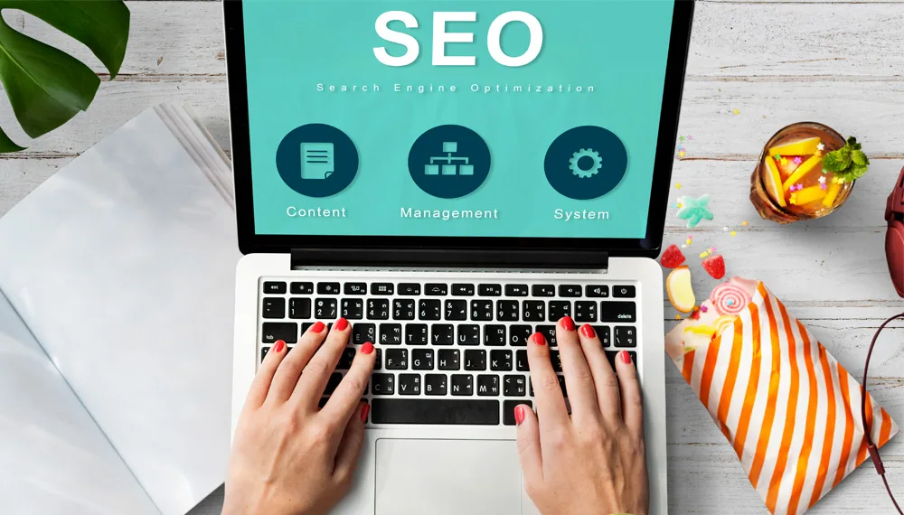 imagem de uma pessoa usando um notebook o texto SEO na tela.